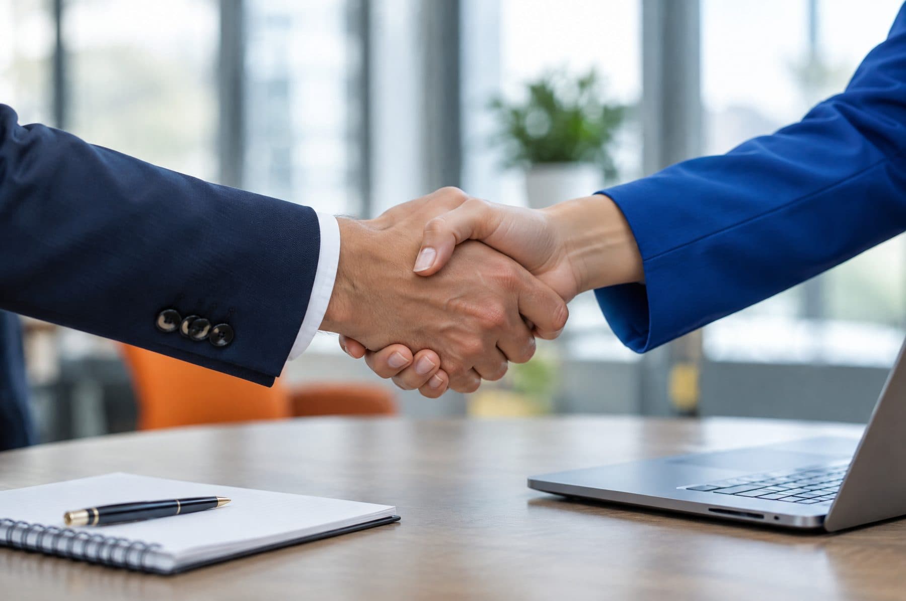 A handshake across a meeting table between two professionals