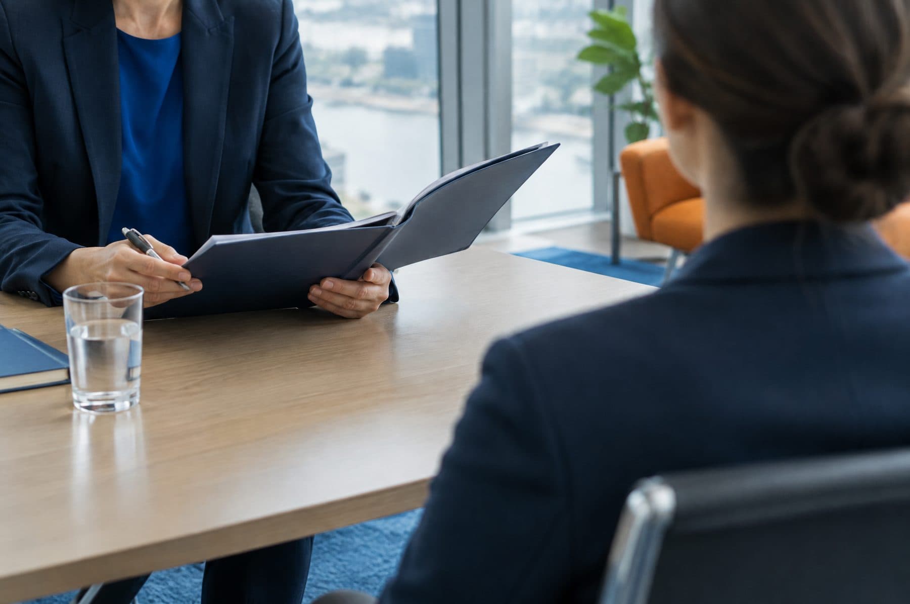 An interview in a glass walled meeting room, photographed over the candidate's shoulder